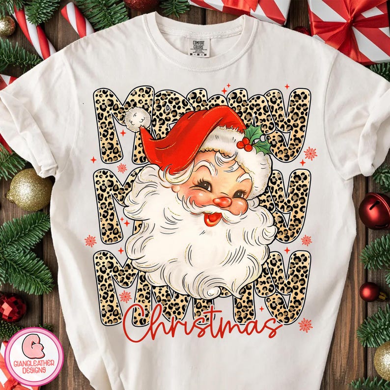 Puede incluir: Camiseta blanca con un dise&ntilde;o de Pap&aacute; Noel con gorro rojo y barba blanca. Las palabras "Merry Christmas" est&aacute;n impresas en la camiseta con una fuente de estampado de leopardo. Ropa festiva navide&ntilde;a.