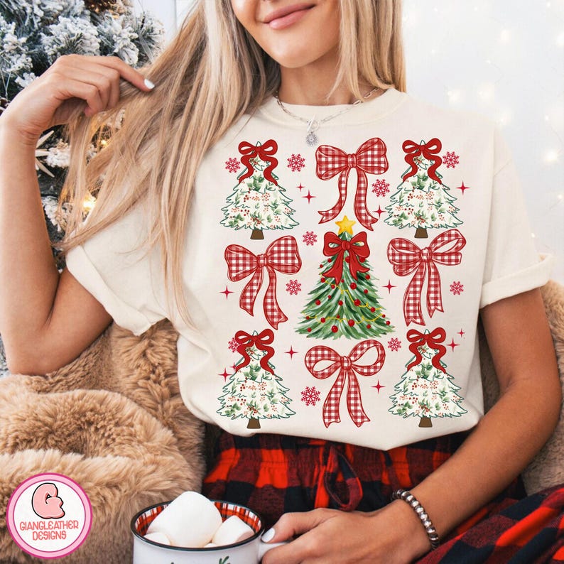 Puede incluir: Camiseta color crema con un dise&ntilde;o navide&ntilde;o. El dise&ntilde;o incluye &aacute;rboles de Navidad, lazos a cuadros rojos, copos de nieve y un &aacute;rbol de Navidad central adornado con una estrella y adornos. Parte de una colecci&oacute;n navide&ntilde;a.