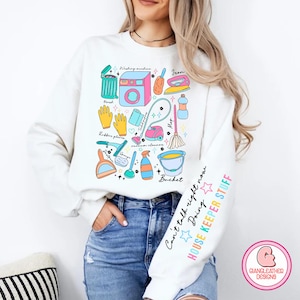 May include: White sweatshirt with a colorful graphic of household cleaning supplies and the text "Can't talk right now Doing HOUSE KEEPER STUFF".