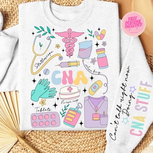 May include: A light grey sweatshirt featuring a colourful CNA design. The design includes a stethoscope, medical symbols, and the words "CNA Stuff" on the sleeve. The words "Can't talk right now Doing" are also on the sleeve.