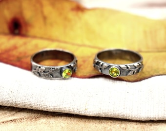 Könnte beinhalten: Zwei silberne Ringe mit einem grünen Edelstein, der in jeden Ring eingefasst ist. Die Ringe haben ein Blattdesign.