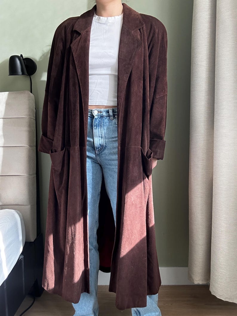 May include: A long brown suede coat with a collar and pockets.