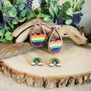 May include: Rainbow heart and rainbow cloud wooden earrings. The earrings are made of wood and painted with rainbow colors. The heart earrings are teardrop shaped and the cloud earrings are small and round.