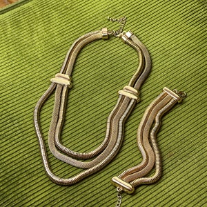 May include: A gold-toned necklace and bracelet set with a chain link design. The necklace is layered with three strands of chain.