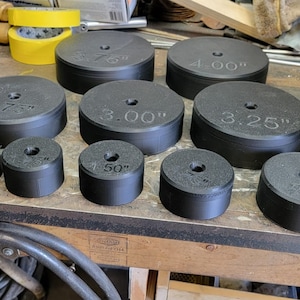 Könnte beinhalten: Ein Satz von 12 schwarzen Plastikkreisen mit verschiedenen Durchmessermaßen in Zoll, darunter 2,50", 2,75", 3,00", 3,25", 3,50", 4,00" und 5,00".