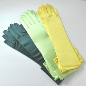 May include: Three pairs of long opera-length gloves made of a smooth, satin-like fabric. The set includes one pair in dark forest green, one pair in light lime green, and one pair in a bright, sunny yellow, all featuring a classic five-finger design.
