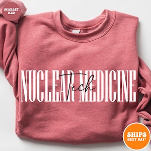 May include: A red sweatshirt with the text "NUCLEAR Tech MEDICINE" in white letters. The text "Tech" is in black cursive.