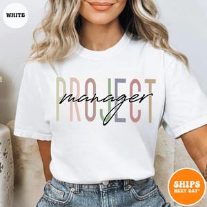 May include: White t-shirt with the text "PROJECT manager" in colorful letters. The text is in a modern, handwritten font.