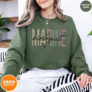 a woman sitting on a couch wearing a green sweatshirt