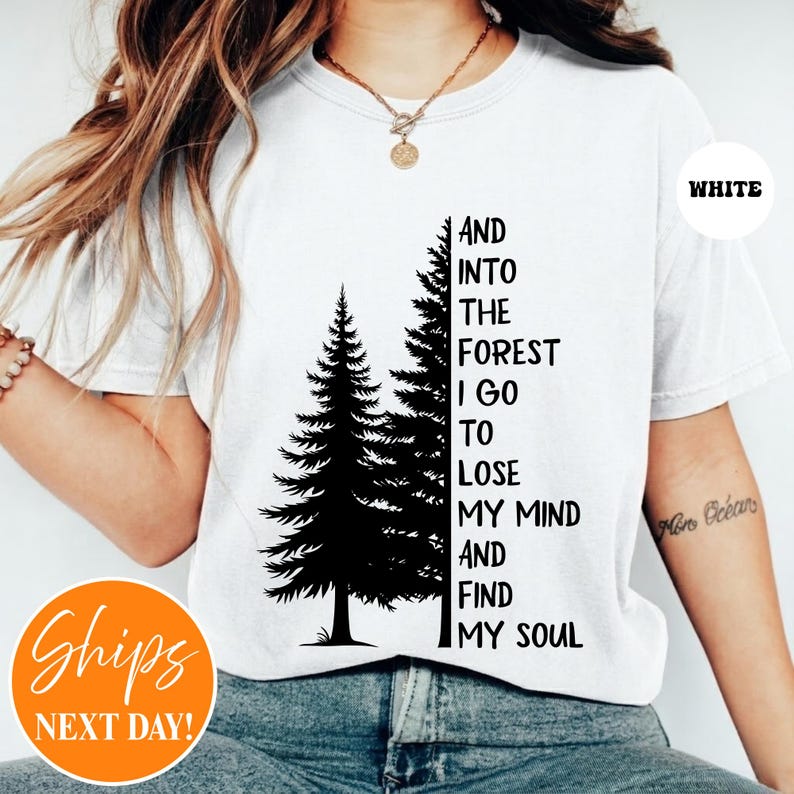 May include: A white short-sleeved t-shirt featuring a black graphic of two pine trees and the text, AND INTO THE FOREST I GO TO LOSE MY MIND AND FIND MY SOUL, printed in a bold, sans-serif font on the front center of the garment.