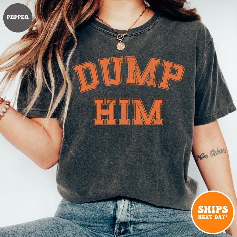 Pu&ograve; includere: Una t-shirt a maniche corte grigio antracite con una stampa grafica arancione in stile college dall'aspetto vissuto sul petto che recita DUMP HIM in grassetto. La maglia presenta un girocollo e un tessuto dall'effetto lavato vintage.