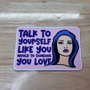 May include: A pink and white sticker with a blue-haired woman and the text "Talk to yourself like you would to someone you love."