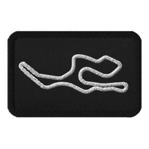 May include: A black embroidered patch with a white outline of a race track.