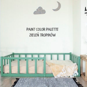 Peut inclure: Un lit pour chien en bois vert avec une couverture blanche et jaune. Le lit est dans une pièce avec un mur blanc et une table en bois. Le texte "PAINT COLOR PALETTE ZIELEN TROPIKÓW" est écrit sur le mur.