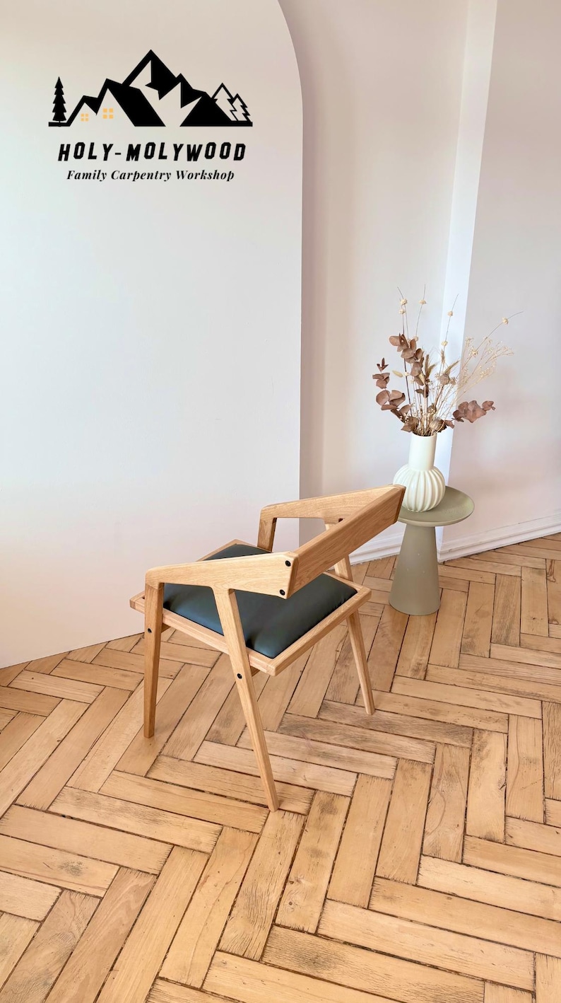 Op de afbeelding: Houten stoel met een donkergrijze zitting en een uniek geometrisch ontwerp. De stoel is gemaakt van lichtgekleurd hout en heeft een moderne uitstraling. De tekst "HOLY-MOLYWOOD Family Carpentry Workshop" is zichtbaar.