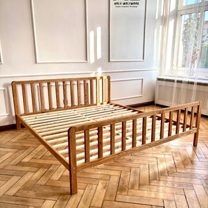 May include: A wooden bed frame with a slatted headboard and footboard, finished in an oak oil stain. The frame features vertical slats and a slatted base. Text on the image reads: HOLY-MOLYWOOD Family Carpentry Workshop and OLEJ - KOLOR DĄB / OIL - COLOR OAK.
