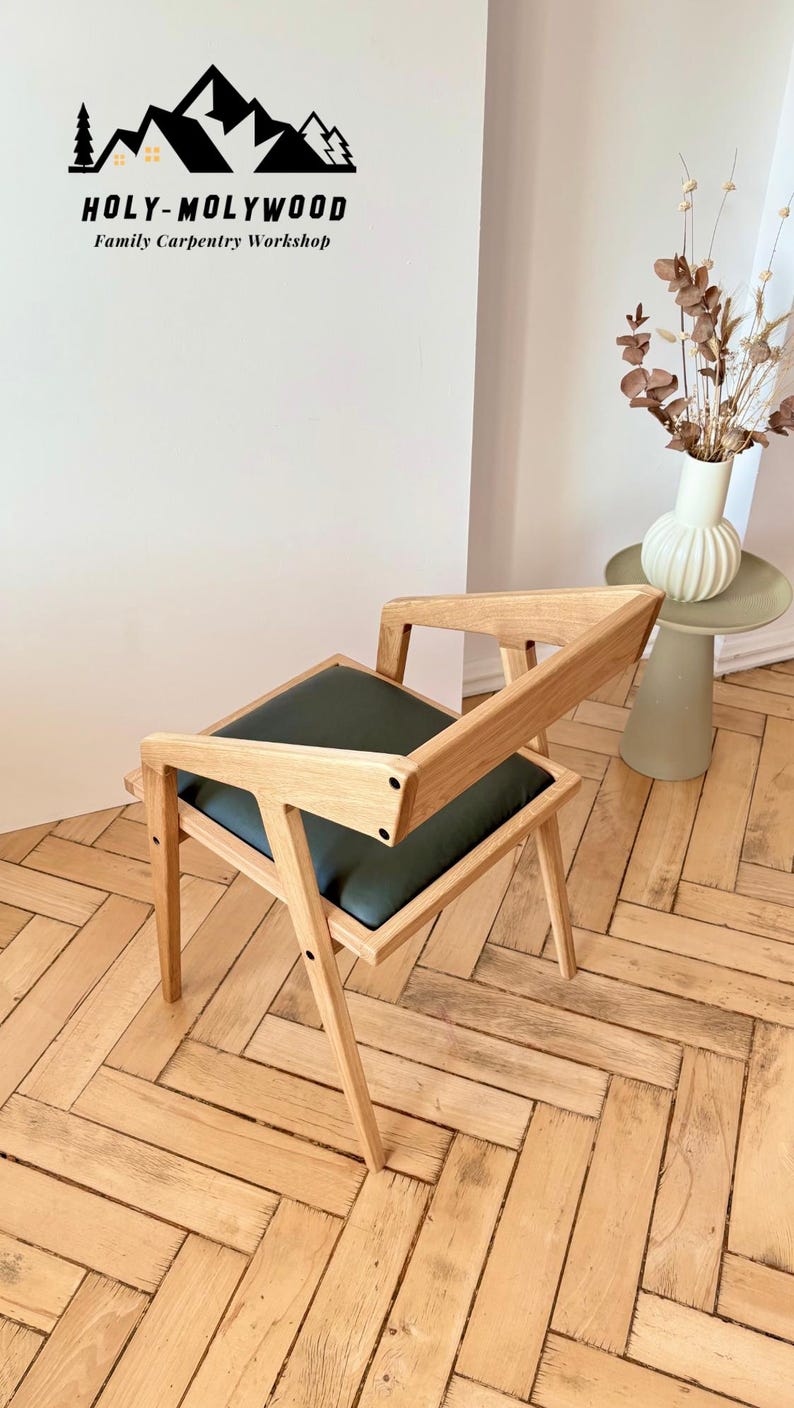 Op de afbeelding: Houten stoel met een donkergroen zitkussen. De stoel heeft een modern ontwerp met schuine poten en rugleuningen. Het logo "HOLY-MOLYWOOD Family Carpentry Workshop" is zichtbaar. De stoel staat op een houten vloer.