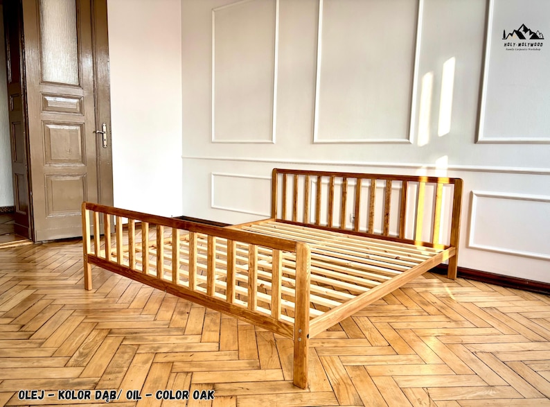 May include: A wooden bed frame with a slatted headboard and footboard, finished in an oak oil stain. The frame features a simple, open design with vertical slats on both ends and a slatted base for mattress support, showcasing the natural wood grain.
