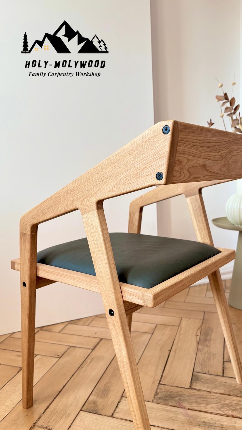 Op de afbeelding: Houten stoel met een donkergroene zitting. De stoel heeft een modern design met een licht houten frame en zwarte hardware. Onderdeel van de Holy-Molywood Family Carpentry Workshop collectie.