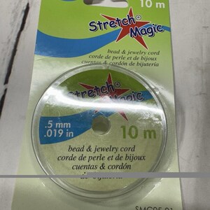 May include: A package of Stretch Magic bead and jewellery cord. The package is green and white, with the words "Stretch Magic" in blue and red. The cord is .5 mm and 10 m long.