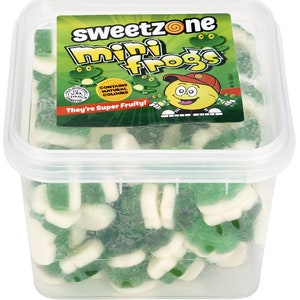 May include: A clear plastic container filled with green and white gummy frog candies. The container has a label that reads "Sweetzone Mini Frogs" with a cartoon frog illustration. The label also states "Contains Natural Colours" and "They're Super Fruity!"