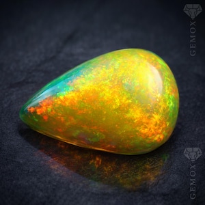 Pode incluir: Uma pedra preciosa de opala em forma de gota, exibindo uma vibrante gama de cores. A opala apresenta uma mistura de tons amarelos, laranja, verdes e vermelhos, com uma superfície polida e brilhante. A gema está sobre um fundo escuro.