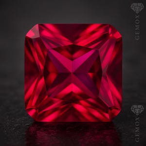 May include: A square-cut ruby gemstone, displaying a vibrant red colour. The facets of the gem reflect light, creating a starburst pattern in the centre. The gemstone is set against a dark background, highlighting its brilliance.