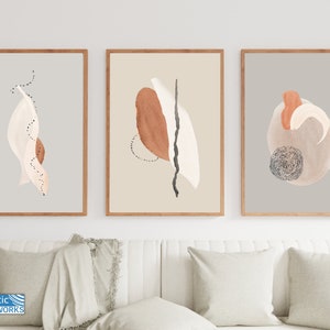 May include: Set of three abstract art prints with brown, beige, and white shapes on a light gray background. The prints are framed in natural wood.