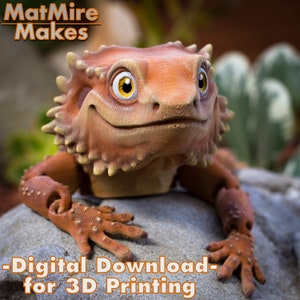 May include: A 3D printed model of a cartoon lizard with a friendly expression. The lizard is brown and orange with yellow eyes. The model is posed sitting on a rock. The text "Digital Download - for 3D Printing" is at the bottom of the image.