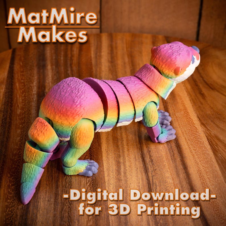 Pode incluir: Uma figura de lontra articulada impressa em 3D com cores de arco-&iacute;ris. A lontra est&aacute; em posi&ccedil;&atilde;o de p&eacute; com a cabe&ccedil;a virada para o lado. O texto "MatMire Makes - Digital Download - for 3D Printing" est&aacute; impresso abaixo da lontra.
