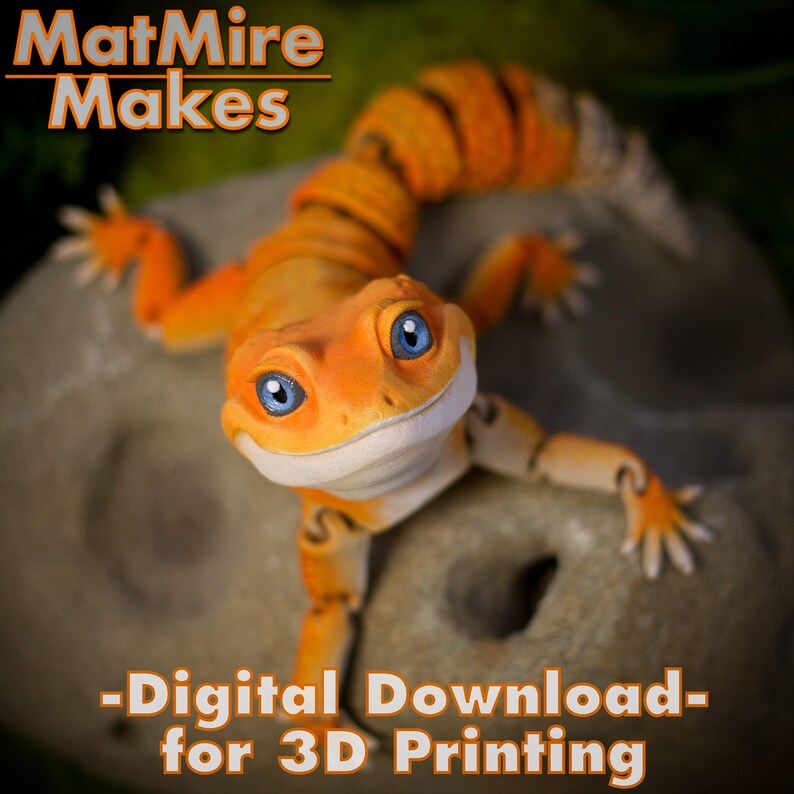 May include: An articulated orange gecko figurine with large blue eyes and a white underbelly. The text MatMire Makes appears at the top, and the text Digital Download for 3D Printing is at the bottom. The gecko has a segmented tail and limbs.
