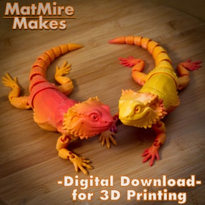 May include: Two 3D printed articulated lizard figurines, one orange and red, the other yellow, on a wooden surface. The text "MatMire Makes - Digital Download - for 3D Printing" is below the lizards.