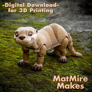 Pode incluir: Um modelo de lontra impresso em 3D, posado em um leito de musgo verde. A lontra &eacute; marrom e tem um corpo segmentado. O texto "Download digital - para impress&atilde;o 3D" est&aacute; na parte superior da imagem. O texto "MatMire Makes" est&aacute; na parte inferior da imagem.