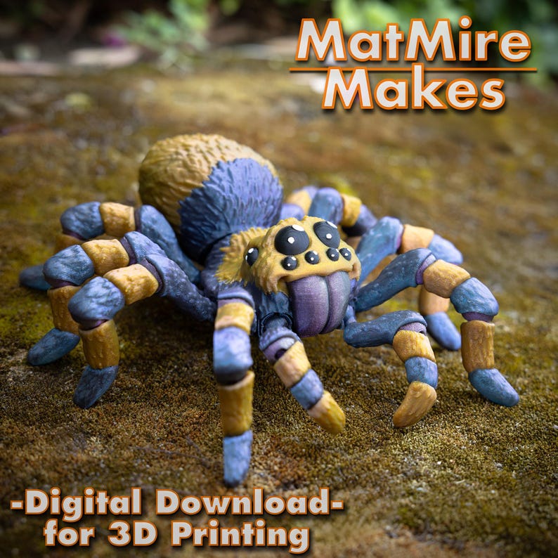 May include: A 3D printed model of a spider with a blue and yellow striped body. The spider has large, black eyes and a purple tongue. The model is sitting on a bed of moss. The text "MatMire Makes - Digital Download - for 3D Printing" is visible at the top of the image.