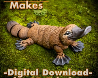 Könnte beinhalten: Ein 3D-gedrucktes Modell eines Schnabeltiers, ein pelziges braunes Säugetier mit einem entenartigen Schnabel, ist auf einem Bett aus grünem Moos platziert. Das Modell ist beweglich und hat einen segmentierten Schwanz. Der Text "MatMire Makes - Digital Download - for 3D Printing" wird unter dem Schnabeltier angezeigt.