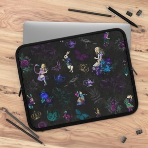 May include: Black laptop sleeve featuring an Alice in Wonderland design. The sleeve is adorned with illustrations of Alice, the White Rabbit, butterflies, crowns, teapots, and flowers in shades of purple, blue, and teal. The sleeve has a black zipper and trim.