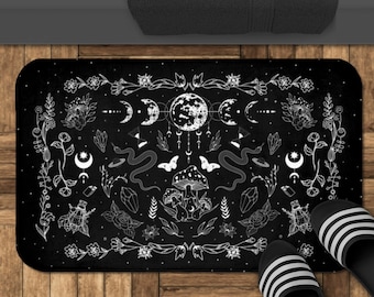 Pode incluir: Tapete de banho preto com um design branco de luas, estrelas, cristais, cogumelos, cobras e flores. O design é centrado em uma lua cheia com uma lua crescente de cada lado.