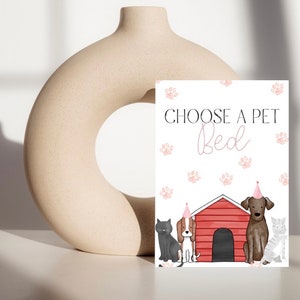 May include: A decorative sign with the text "CHOOSE A PET Bed" in black and pink. The sign features illustrations of a black cat, a beagle, a brown dog, and a gray cat, all wearing party hats, in front of a red dog house.
