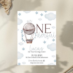 Puede incluir: Una tarjeta de invitación de acuarela con un diseño de globo aerostático. La tarjeta presenta el texto "Mr. One derful" y "Lucas cumple un año" con la fecha y la hora. El diseño incluye nubes y estrellas.