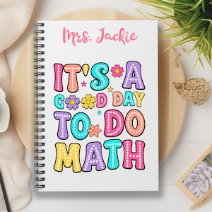 May include: A white spiral-bound notebook featuring the pink text Mrs. Jackie at the top. Below, the colorful text reads IT'S A GOOD DAY TO DO MATH in a bubble font with white dots, accented by small flower and star icons in pink, yellow, and blue.