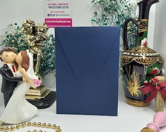 May include: A navy blue envelope with a white flap. The envelope is sitting on a white surface. The text on the card reads "Davetiye Dunyasi" and includes a phone number and website address.