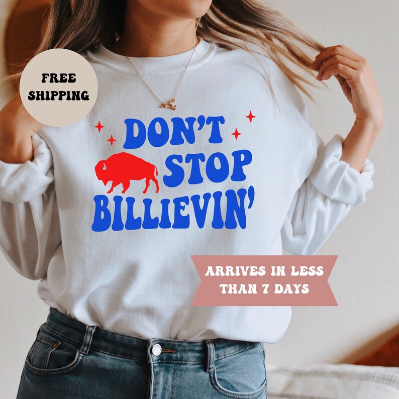 May include: White sweatshirt with a blue and red graphic that says "Don't Stop Believin'" with a red buffalo silhouette. The text is in a retro font.