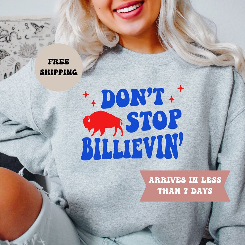 May include: Gray sweatshirt with a blue and red graphic that says "Don't Stop Billievin'" with a red buffalo silhouette. The text "Arrives in less than 7 days" is also on the sweatshirt.