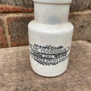 May include: White ceramic jar with black lettering that reads "The Cunningham and De Fourier Co. Ltd. London".