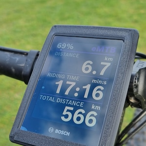 May include: A black and grey eMTB bike display shows the distance travelled, riding time, and total distance. The display reads 6.7 km, 17:16, and 566 km. The display is labelled "BOSCH".