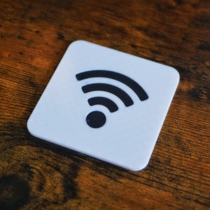 Op de afbeelding: Een witte vierkante onderzetter met een zwart wifi-symbool.