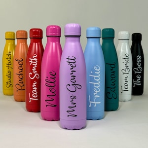 May include: A row of ten colourful stainless steel water bottles with personalised names, including "Studio Hitch", "Rachael", "Team Smith", "Mollie", "Mrs. Garrett", "Freddie", "Edwsond", "Team Bride", and "The Boss".
