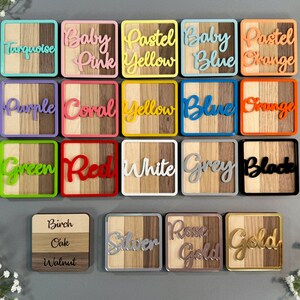 May include: A collection of colorful wooden coasters with various color names in cursive script. Each coaster features a wooden design with a colored border and a matching color name. Colors include turquoise, baby pink, pastel yellow, baby blue, and pastel orange.