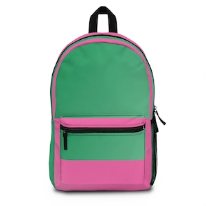 May include: A green and pink backpack with a zippered front pocket. The backpack has a black zipper and black straps.