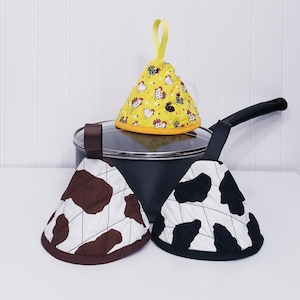 Puede incluir: Tres agarraderas para ollas. Una agarradera amarilla con estampado de pollo. Dos agarraderas con estampado de vaca, una marrón y blanca, una negra y blanca.